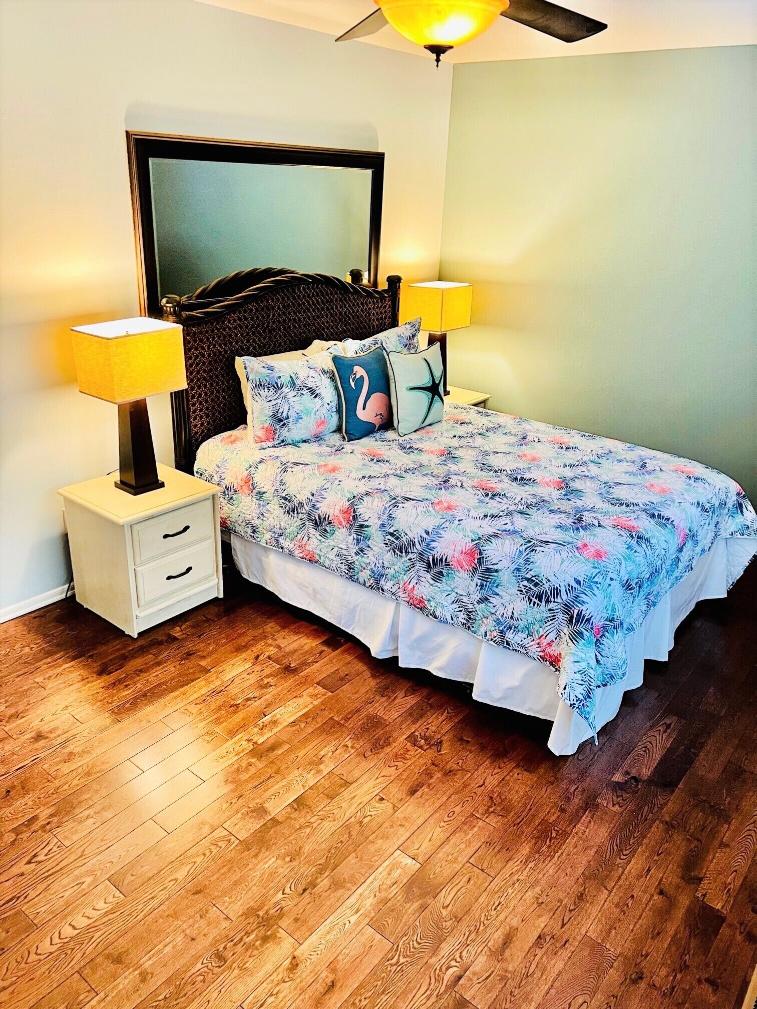 Una camera da letto con un letto, due comodini, un tavolino e una grande ventola a soffitto sopra il letto.