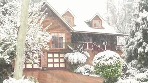 Una casa de madera con techo nevado y un porche delantero.