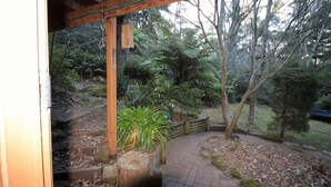 Una pérgola de madera con un sendero que atraviesa un jardín con diversas plantas y árboles.