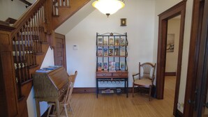 A wooden staircase, a reading bench, a bookcase, and a chair in a room with wooden flooring.