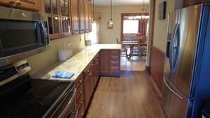 A kitchen with wooden cabinets, stainless steel appliances, and a dining area with a table and chairs.
