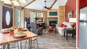 A cozy cabin interior with a dining table set for a meal, a fireplace, and a comfortable seating area. - Gnoming Around (Gatlinburg)