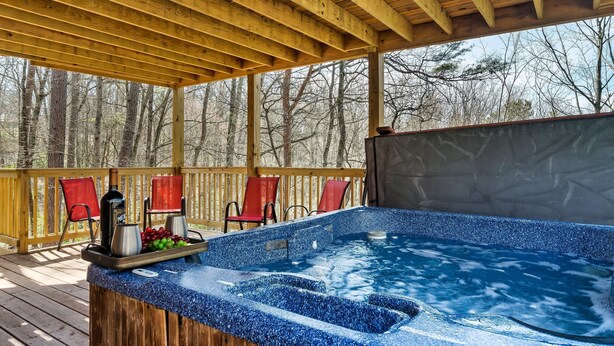 A wooden deck with a hot tub, red chairs, and a wooden pergola. - Gnoming Around (Gatlinburg)