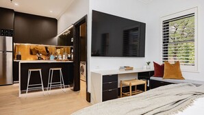 Une chambre moderne avec un grand lit, un bureau avec une chaise et un téléviseur fixé au mur.