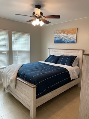 Un dormitorio con cama de madera, ventilador de techo y un cuadro en la pared.