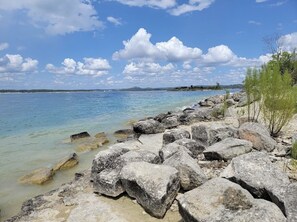 A rocky shoreline with clear water and a distant view of land.