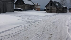 Zona rural con construcciones de madera y suelo cubierto de nieve.