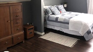 Un dormitorio con cama, cómoda, mueble auxiliar y alfombra.
