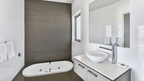 A modern bathroom with a freestanding bathtub, a white sink, and a large mirror above the vanity. - Robe Highview (Robe)