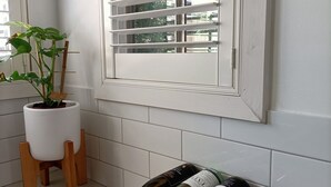 Un coin de pièce avec une fenêtre, une plante en pot et un porte-bouteilles en bois contenant plusieurs bouteilles de vin.
