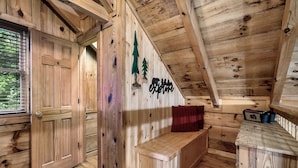L’intérieur d’une cabane en bois, avec un banc en bois, une porte et un mur décoré avec un motif d’arbre.