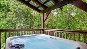 Un bain à remous sur une terrasse en bois, entouré d’une végétation luxuriante.