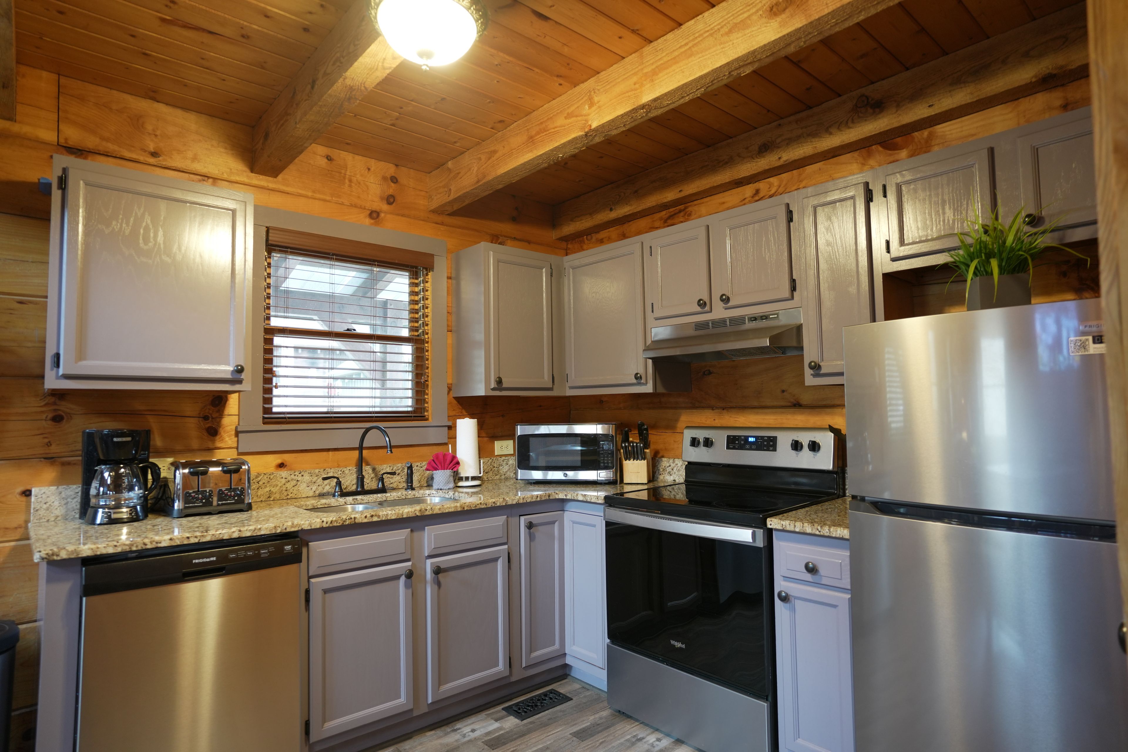 A modern kitchen with stainless steel appliances, wooden cabinets, and a granite countertop.