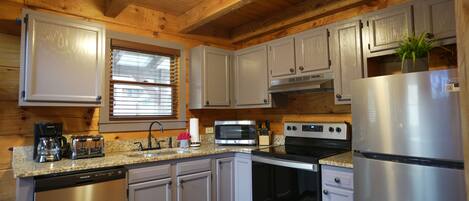 A modern kitchen with stainless steel appliances, wooden cabinets, and a granite countertop.