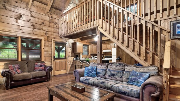 Un intérieur en bois comprenant un escalier, deux canapés, une table basse et des meubles de rangement en bois.