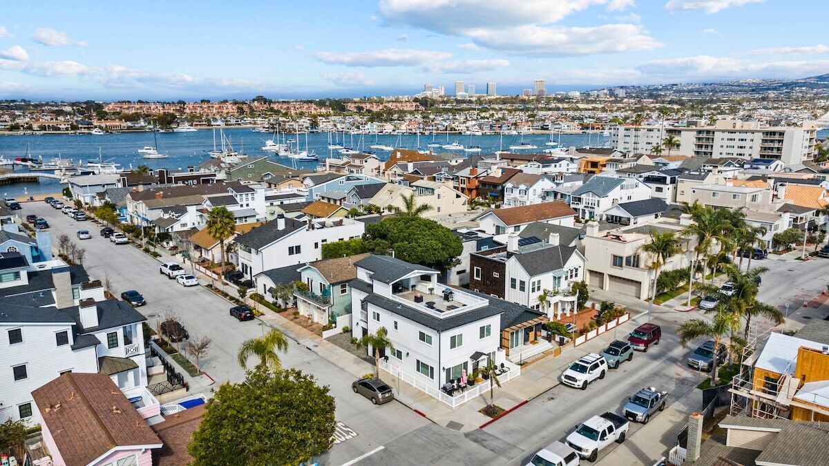 Una zona residencial costera con casas, un puerto deportivo y el perfil distante de una ciudad.