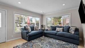 A living room with two dark blue sofas, a patterned rug, and a flat-screen TV mounted on the wall.