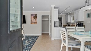 A modern kitchen with white cabinetry, a dining table, and a blue rug.