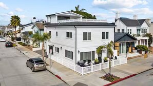 A two-story white house with a balcony, a garage, and a front porch with outdoor seating.