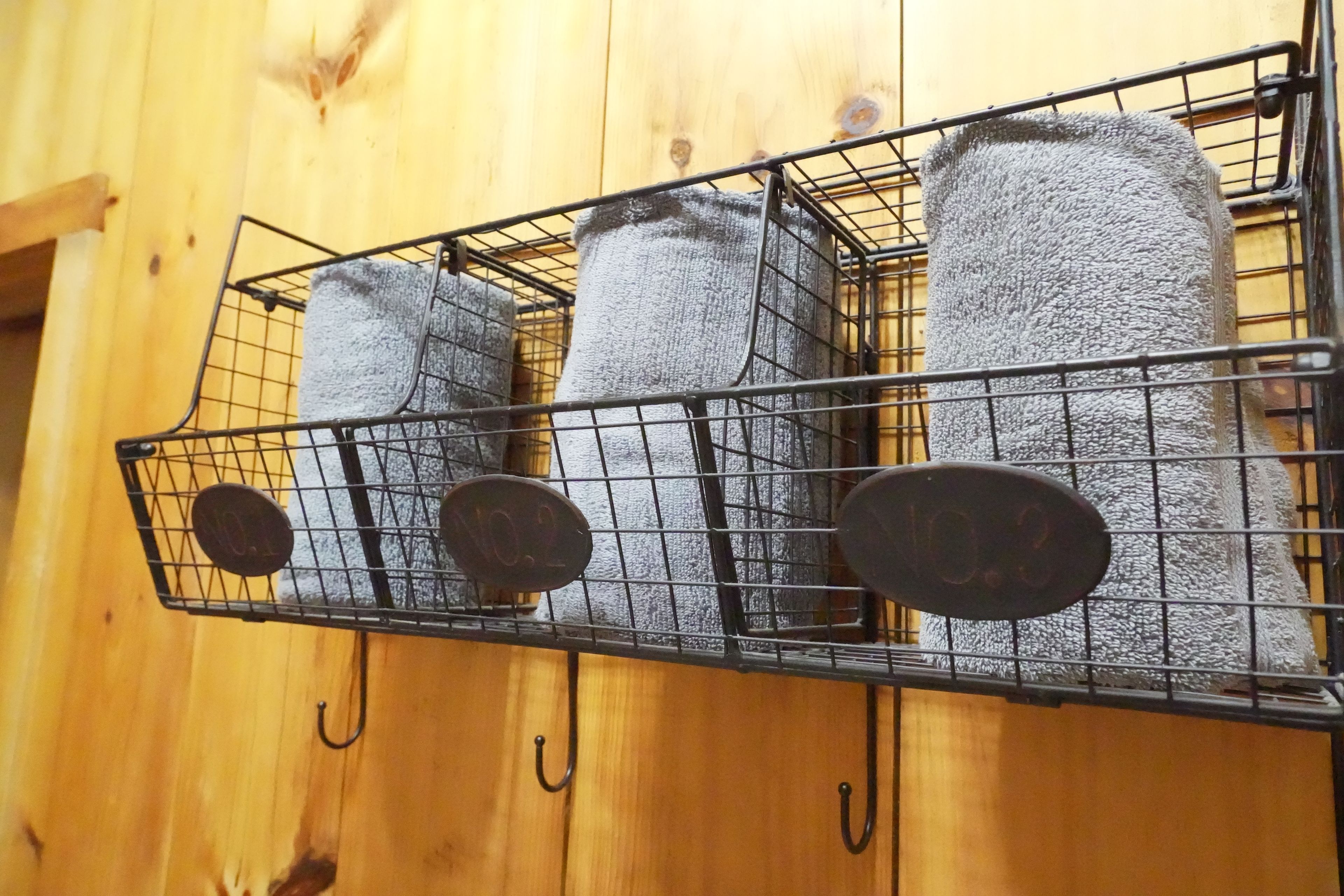 A metal rack with three rolled-up towels hanging on hooks.