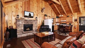 A cozy cabin interior with a stone fireplace, leather furniture, and wooden walls. - Moonshine Holler (Sevierville)