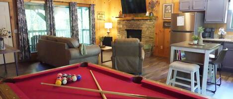 A cozy room with a pool table, a fireplace, and a television.
