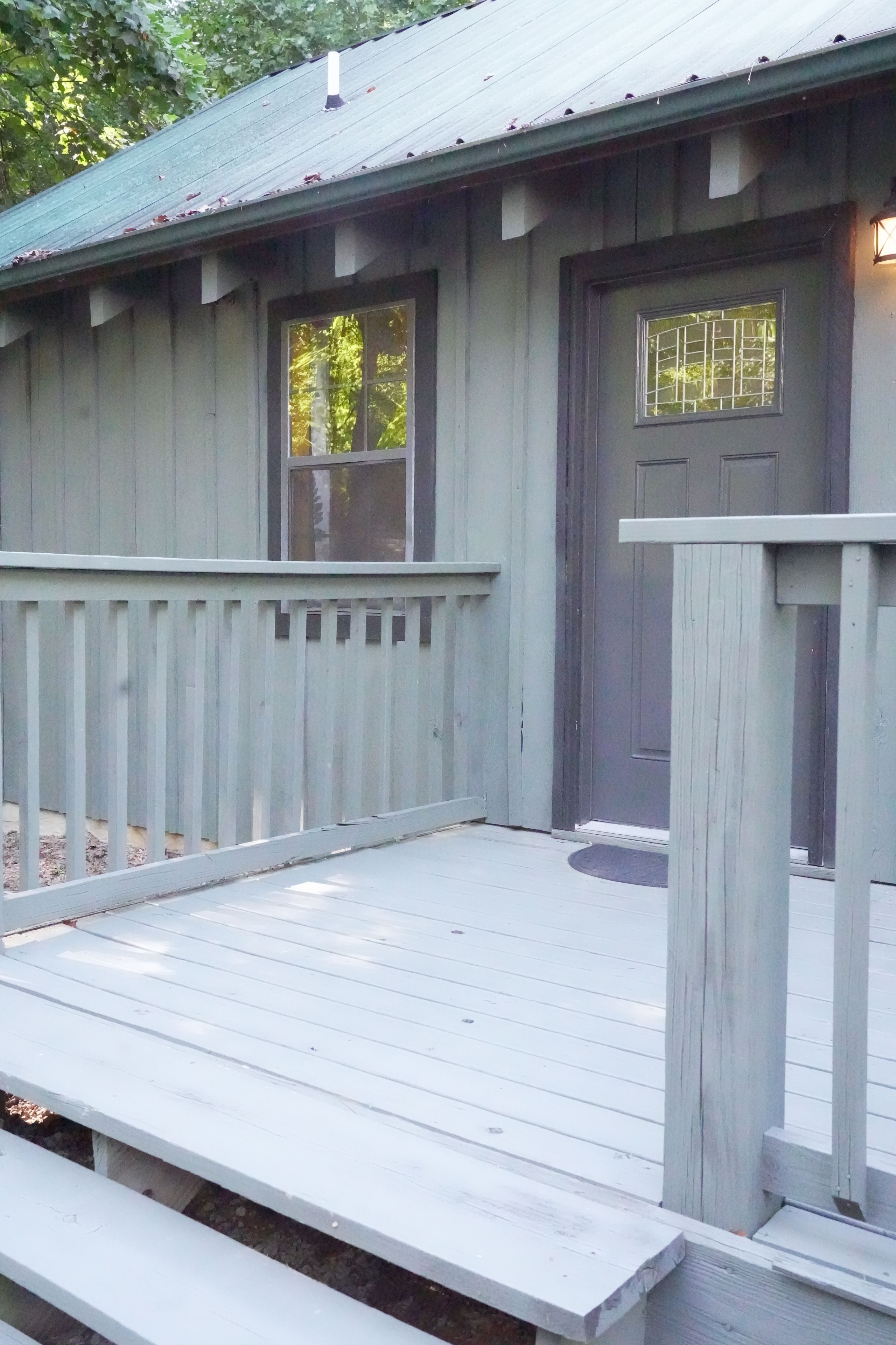 A wooden cabin with a porch, a door, and two windows.