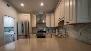 A modern kitchen with white cabinets, stainless steel appliances, and a granite countertop. - Charming Beach Cottage, Beach Chair Service Included. Snowbirds special rates! (Miramar Beach)