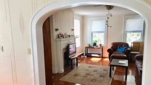 Ein großzügiges Wohnzimmer mit Holzdielen, einem Kamin, einem Fernseher und einer gemütlichen Sitzecke.