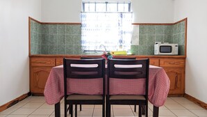 Une cuisine avec deux chaises, une table, une fenêtre et un four à micro-ondes.
