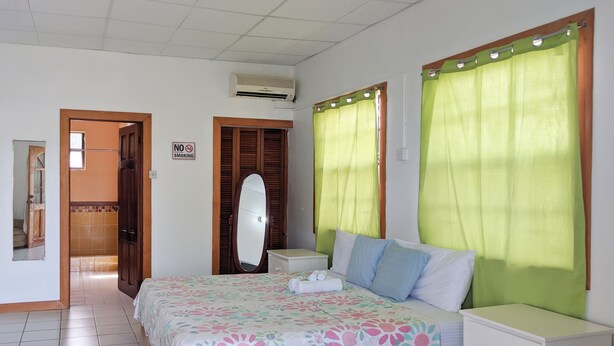 Une chambre à coucher comprenant un lit, une table de chevet, une commode, un miroir, une porte et un panneau indiquant qu’il est interdit de fumer.