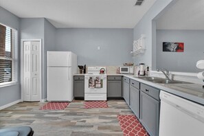 Compact kitchen with a stove, refrigerator, sink, and microwave, perfect for preparing meals.