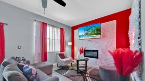 Una sala de estar moderna con un televisor de pantalla plana, un sofá, un sillón y una mesa de centro.