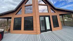 En moderne hytte med stor terrasse, mange vinduer og en markant tagkonstruktion.