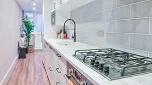A modern kitchen with a gas stove, white cabinets, and a grey tiled backsplash.