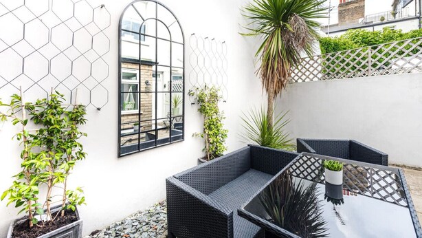 A patio with wicker furniture, a mirror, and potted plants.