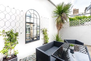 Une terrasse avec des meubles en osier, un miroir et des plantes en pot.