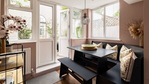 A modern room with a black sofa, a dining table, and large windows.