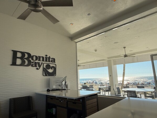 A modern interior with a 'Bonita Bay' sign, a ceiling fan, and a view of the beach.