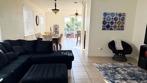 A living room with a sectional sofa, a coffee table, a patterned rug, a dining area with a table and chairs, and a ceiling fan. - Cozy home on the water with plenty of sleep space (Fort Myers)