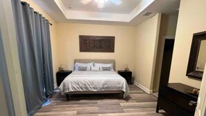 A bedroom with a bed, nightstands, a dresser, and a ceiling fan. - Cozy home on the water with plenty of sleep space (Fort Myers)