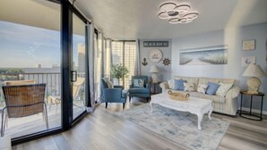 A spacious living room with a balcony, a sofa set, and a coffee table. - Penthouse Condo with spectacular views and sunsets (Panama City Beach)