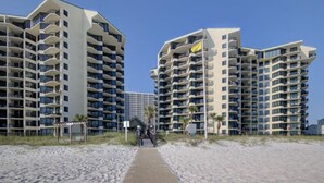 A beachfront hotel with multiple high-rise buildings, a sandy beach, and a wooden boardwalk leading to the entrance. - Penthouse Condo with spectacular views and sunsets (Panama City Beach)