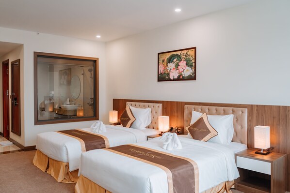 Habitación de hotel con dos camas, un espejo grande, un cuadro y una mesita de noche con lámpara.