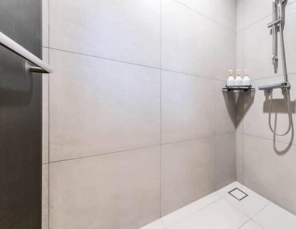 Un área de ducha moderna con un cabezal de ducha de mano y un grifo empotrado en la pared.