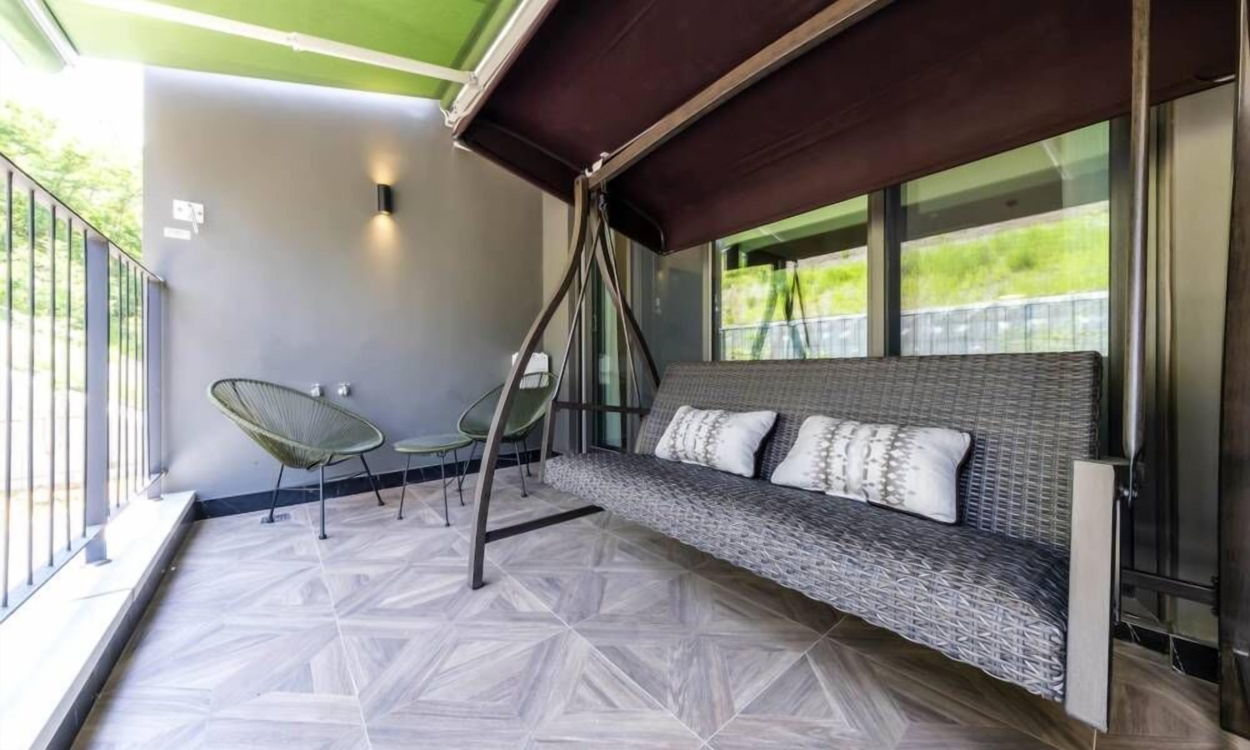 A balcony with a cushioned seating area, a small table, and chairs.