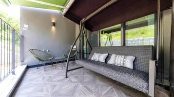 A balcony with a cushioned seating area, a small table, and chairs.