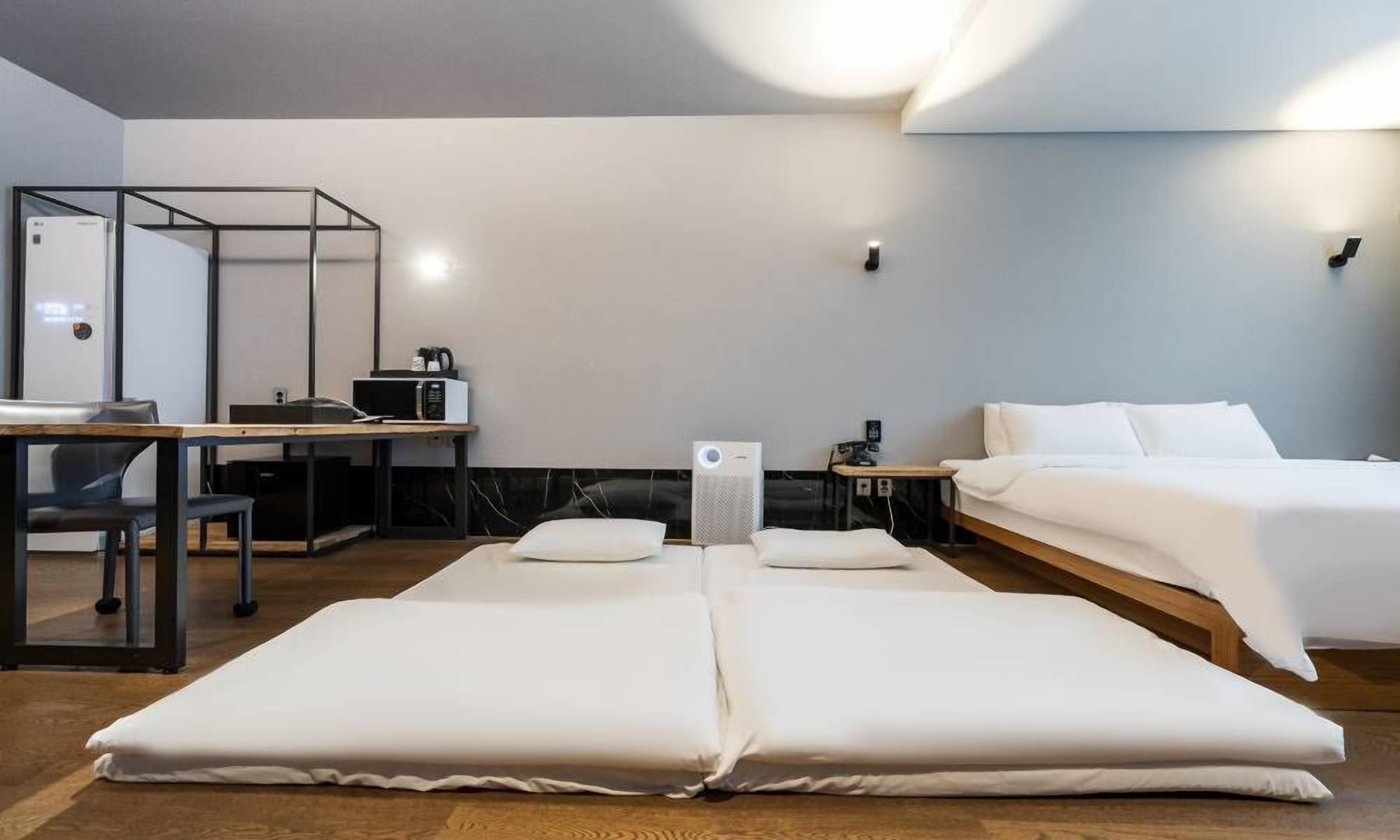 Habitación de hotel con cama, escritorio, silla, microondas y altavoz.