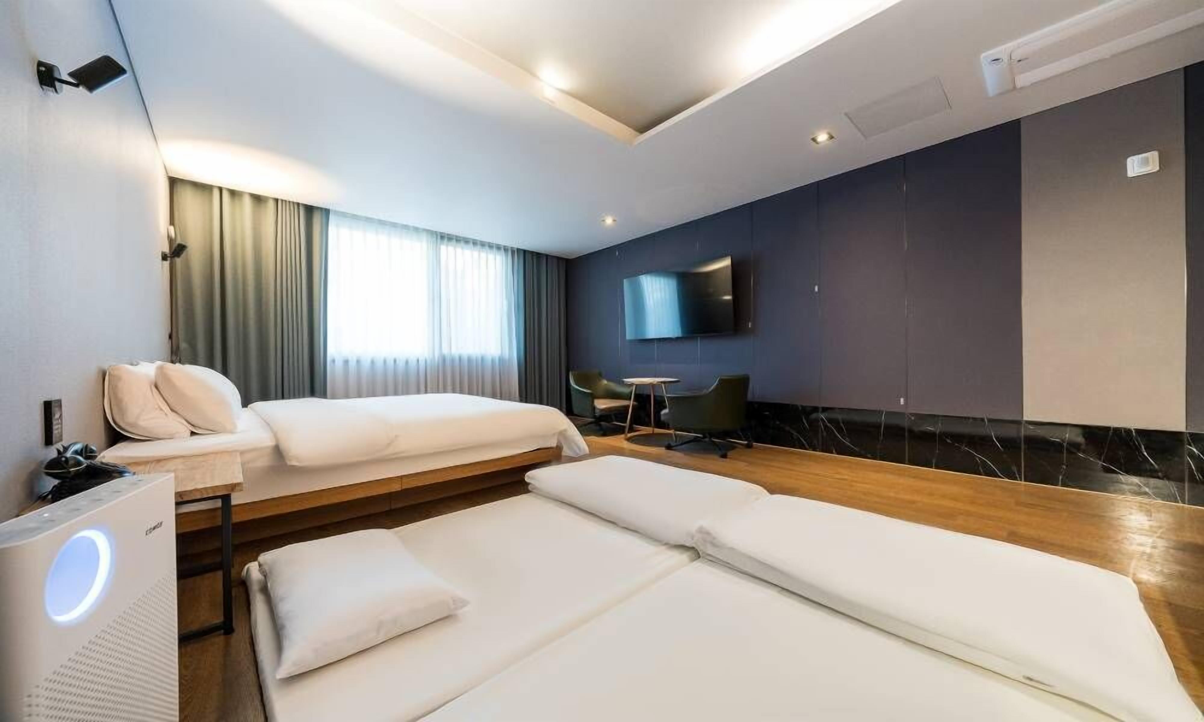 Habitación de hotel con dos camas, televisión, escritorio y una silla.
