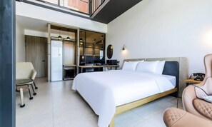 Una habitación de hotel moderna con una cama grande, un escritorio, una silla y un armario.